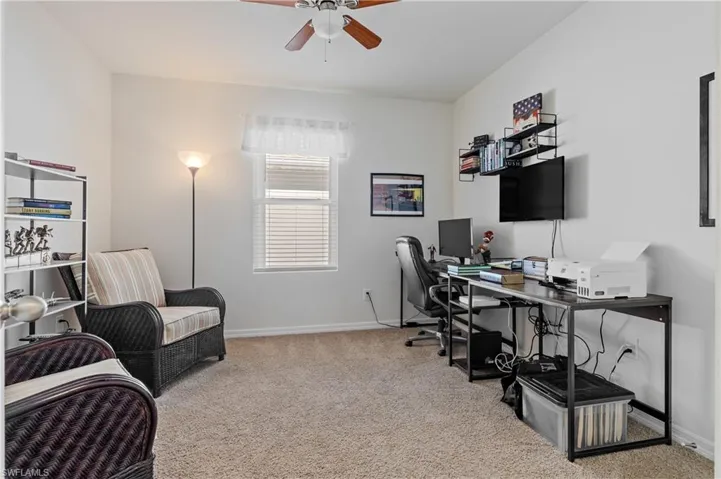 Home office with light carpet and ceiling fan