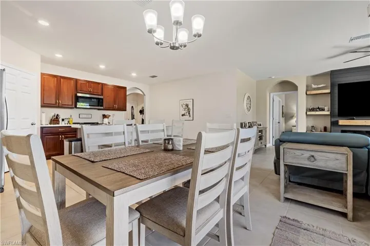Dining space featuring arched walkways, hanging lights, and light tile patterned flooring
