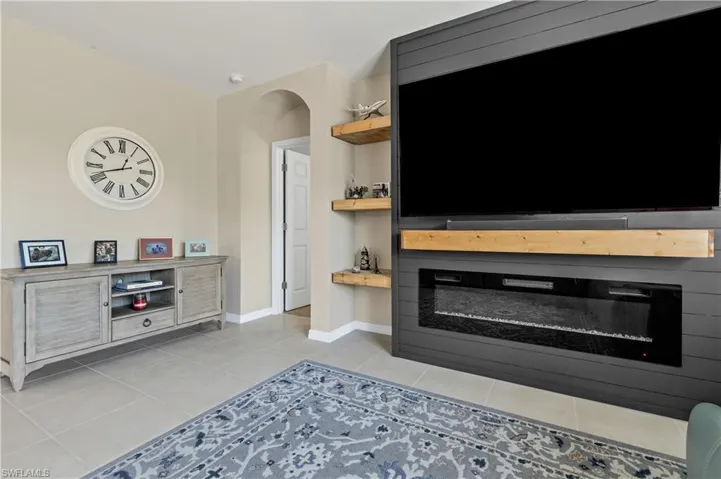 Living area featuring a glass covered fireplace, light tile patterned flooring, and arched walkways