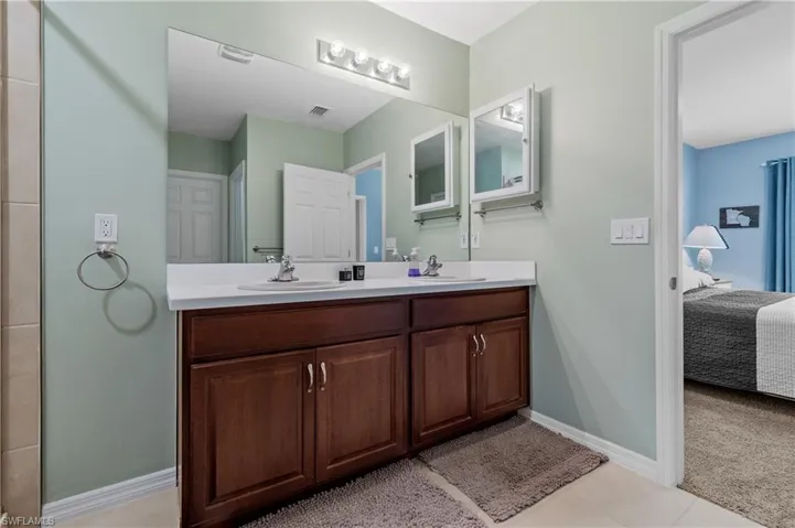 Full bathroom with double vanity, ensuite bathroom, and light colored carpet