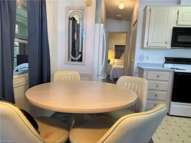 Dining area with light floors, a textured ceiling, and wallpapered walls