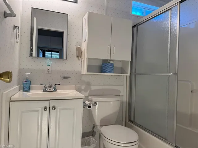 Bathroom with toilet, vanity, and wallpapered walls
