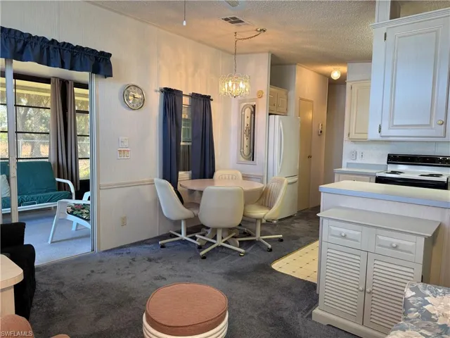 Dining space with a notable chandelier, visible vents, dark carpet, and a textured ceiling