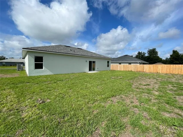 Back of property with a lawn and central air condition unit