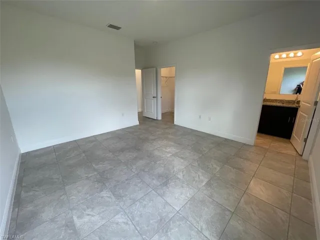 Unfurnished bedroom featuring a walk in closet, ensuite bathroom, and a closet