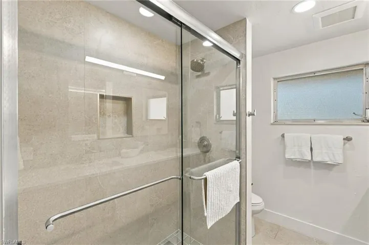 Guest bath withGlass-enclosed shower and integrated light fixture