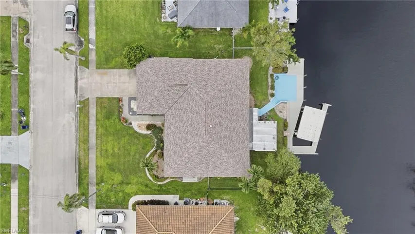 Waterfront property featuring a private boat dock, concrete driveway, and boat lift