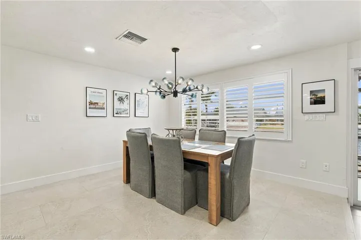 Recessed ceiling lighting, modern chandelier, tile flooring, and a large window with plantation shutters