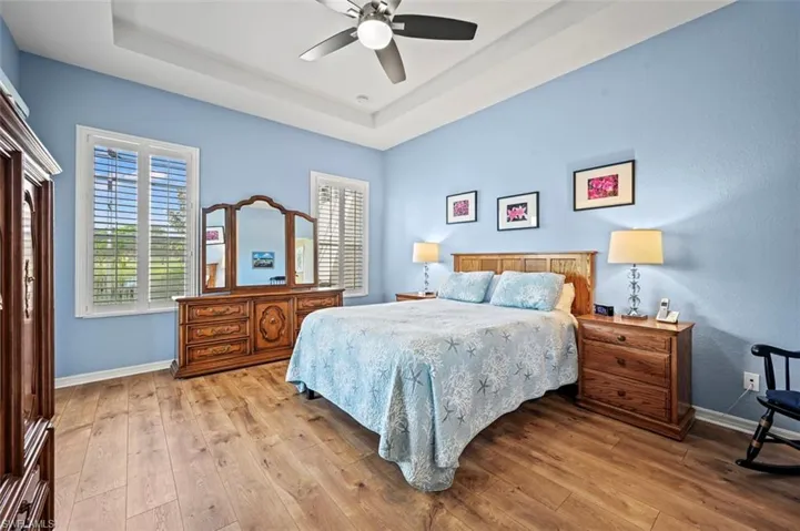 Bedroom featuring a tray ceiling, light wood-type flooring, and ceiling fan