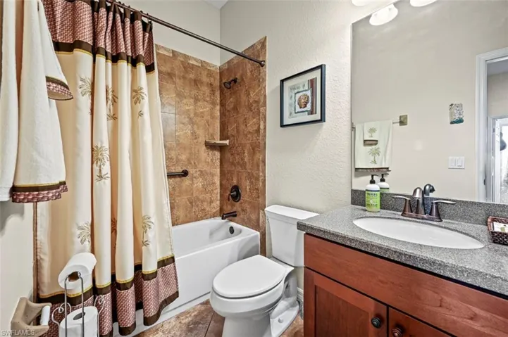 Full bathroom with tile patterned floors, vanity, shower / bathtub combination with curtain, and toilet
