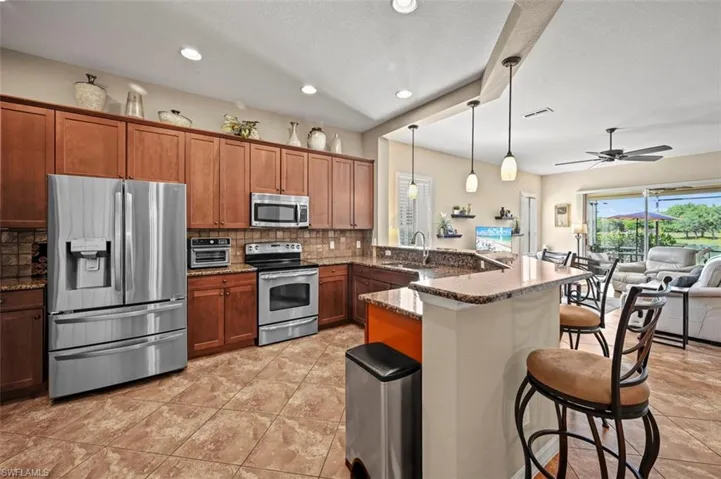 Kitchen with ceiling fan, stainless steel appliances, a kitchen bar, kitchen peninsula, and backsplash
