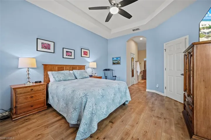Bedroom featuring a raised ceiling, hardwood / wood-style floors, and ceiling fan