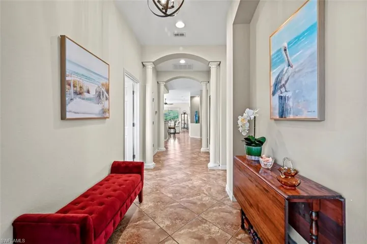 Hall featuring decorative columns and tile patterned floors