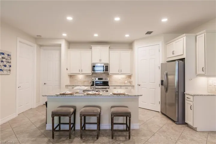 Kitchen with a center island with sink, sink, appliances with stainless steel finishes, and white cabinets