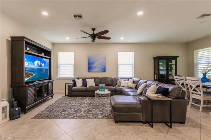 Living room with ceiling fan and light tile patterned flooring