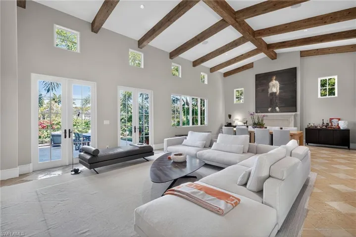 Living room with french doors, beamed ceiling, healthy amount of natural light, and high vaulted ceiling