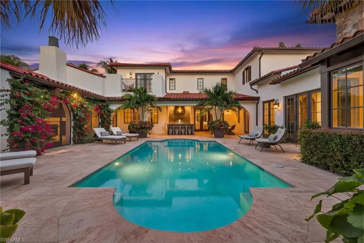 Pool at dusk featuring a patio area, an outdoor pool, and french doors