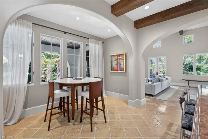 Dining area featuring stone tile flooring, arched walkways, french doors, recessed lighting, and beam ceiling