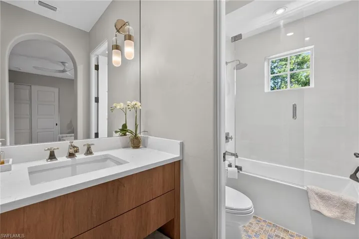 Bathroom with bath / shower combo with glass door and vanity