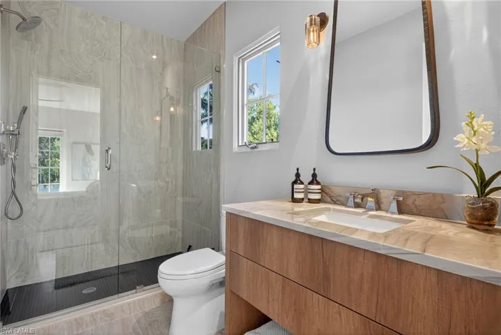 Full bathroom with healthy amount of natural light, a marble finish shower, and vanity