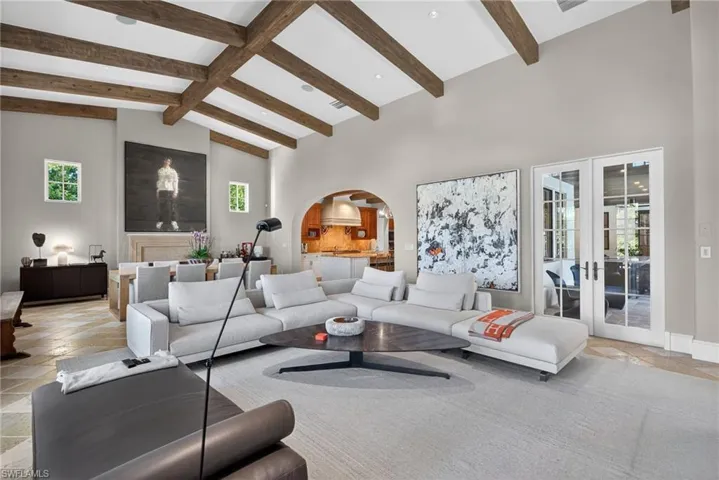 Living area with stone tile floors, arched walkways, french doors, plenty of natural light, and high vaulted ceiling