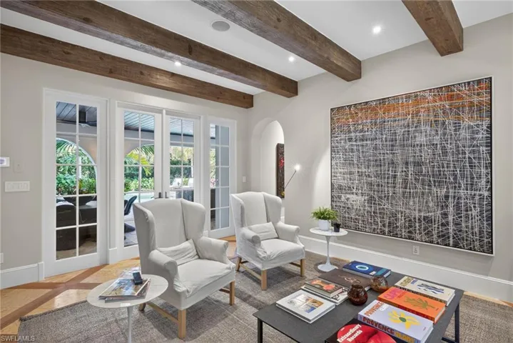 Living room featuring french doors, recessed lighting, inlaid floor details, arched walkways, and beam ceiling