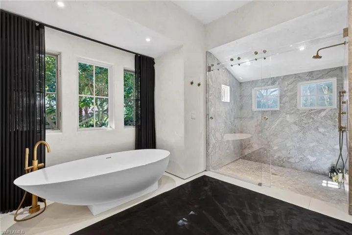 Bathroom with a freestanding tub and a marble finish shower