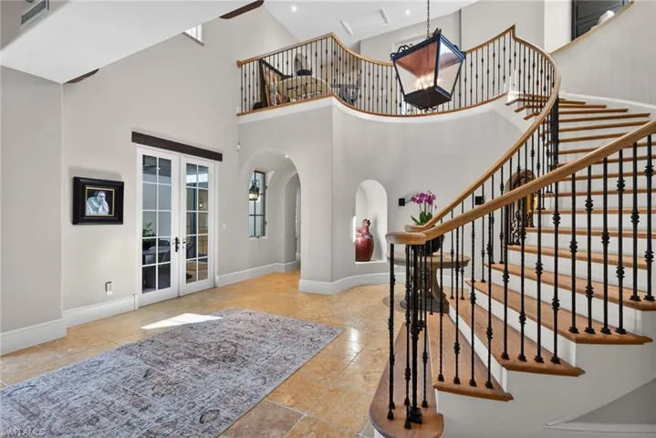 Staircase with french doors, arched walkways, and a towering ceiling