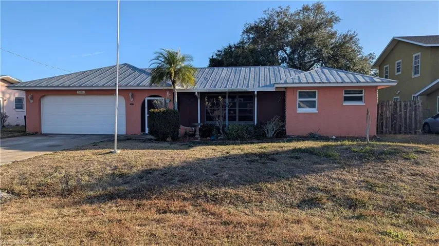 Ranch-style house with a metal roof, stucco siding, an attached garage, and driveway