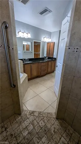 Full bath with double vanity, a bath, tiled shower, and light tile patterned flooring