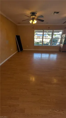 Empty room with crown molding, a ceiling fan, and wood finished floors