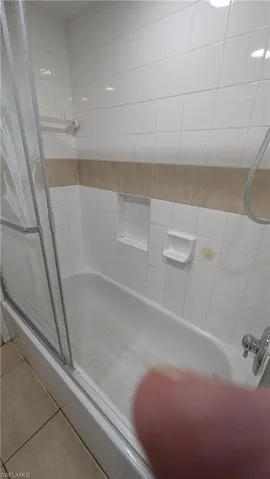 Full bath with a shower with shower door and tile patterned floors