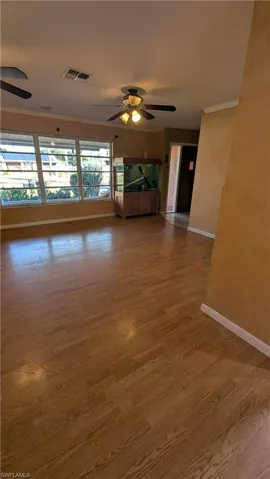 Empty room featuring ornamental molding, light wood-style flooring, and a ceiling fan