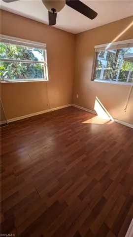 Spare room with healthy amount of natural light, dark wood finished floors, and a ceiling fan