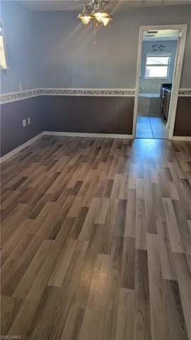 Empty room featuring plenty of natural light, wainscoting, and dark wood-type flooring