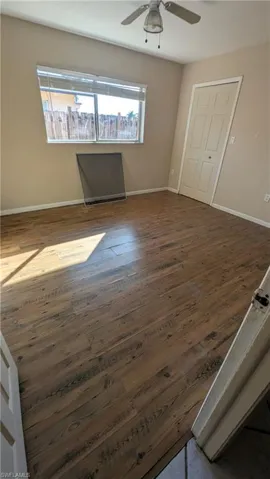 Unfurnished bedroom with dark wood-style floors and a ceiling fan