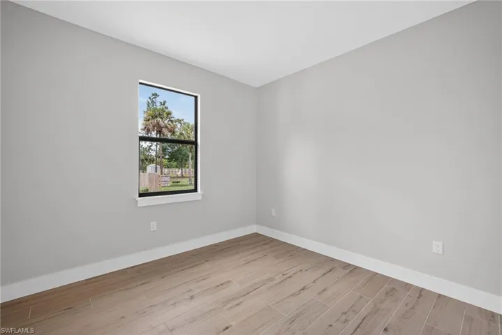 Room featuring neutral gray walls, bright white baseboards, and wood-finish tile flooring