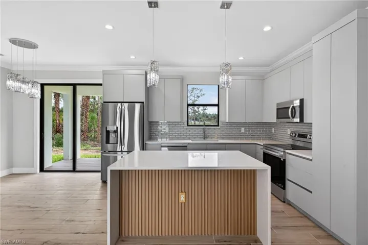 Modern kitchen featuring white shaker cabinetry and a light-toned wood-finish flooring