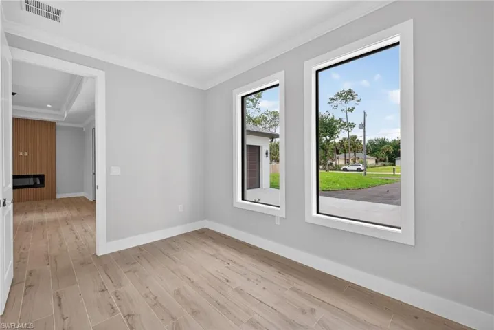 Spacious interior room with light wood-finish flooring and two tall rectangular windows