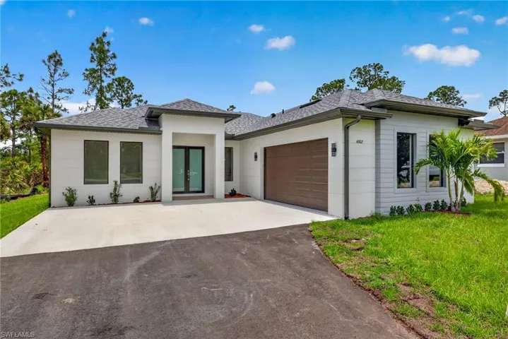 Modern single-story residence featuring a two-car garage with a wood-finish door, a covered entry with double glass doors, and a concrete driveway