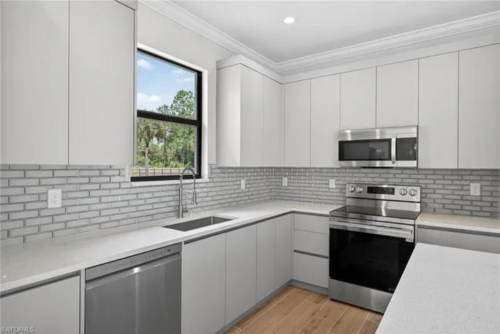Modern kitchen featuring light gray flat-panel cabinetry and stainless steel appliances