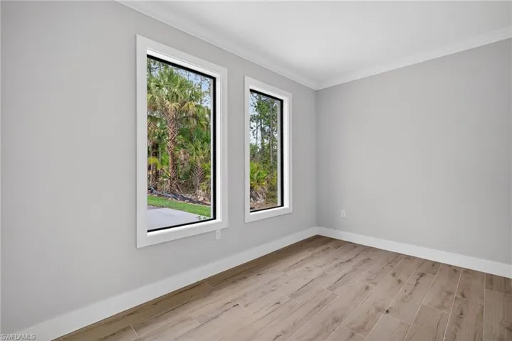 Interior room featuring light gray walls, two vertical windows with white trim, and wood-finish tile flooring