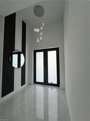 Entrance foyer with french doors and a chandelier