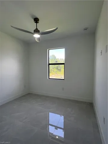 Unfurnished room featuring a ceiling fan and baseboards