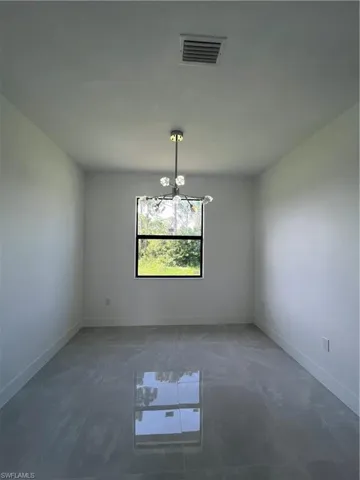 Unfurnished room with a chandelier and baseboards