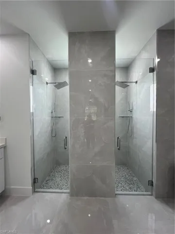Full bathroom featuring a shower stall, marble finish floors, and vanity