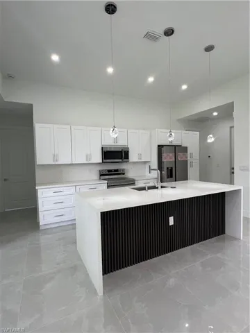 Kitchen featuring stove, refrigerator, white cabinetry, a spacious island, and recessed lighting