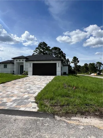 Prairie-style home featuring decorative driveway, an attached garage, and stucco siding