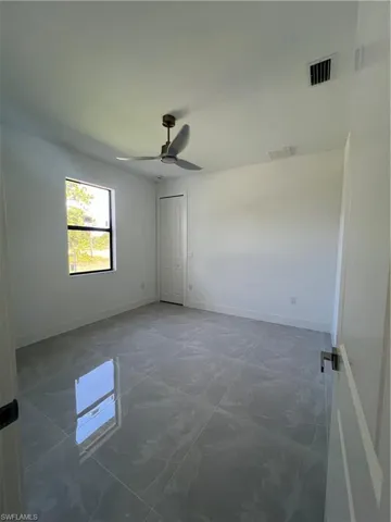 Unfurnished room featuring marble finish floors and a ceiling fan