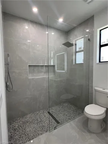 Full bath with walk in shower, marble finish flooring, and recessed lighting